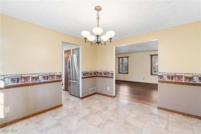 unfurnished dining area with an inviting chandelier, baseboards, and visible vents