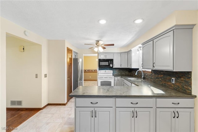 kitchen featuring electric range, visible vents, a sink, freestanding refrigerator, and black microwave