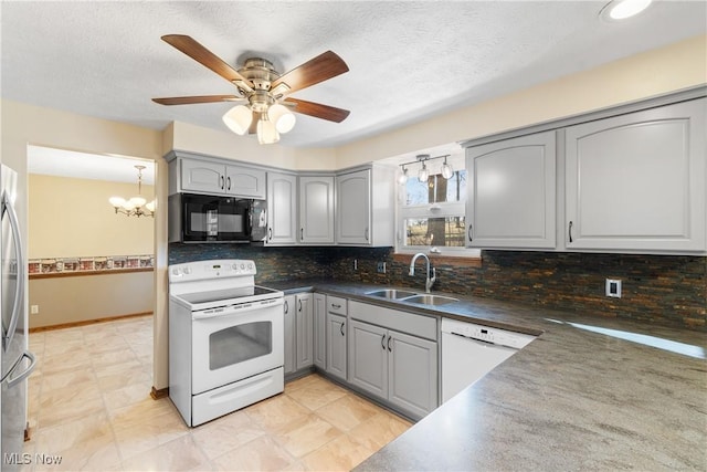 kitchen featuring dark countertops, tasteful backsplash, gray cabinets, white appliances, and a sink