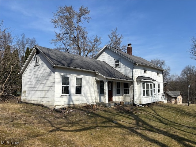 view of front of home with a front yard and a shingled roof