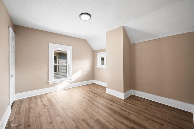 bonus room featuring baseboards, lofted ceiling, and wood finished floors