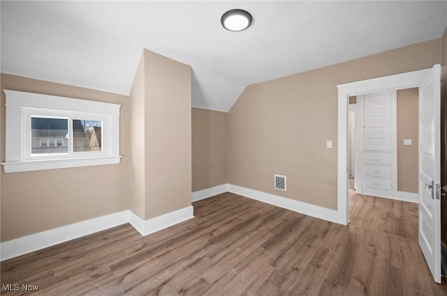 additional living space featuring visible vents, baseboards, lofted ceiling, and wood finished floors