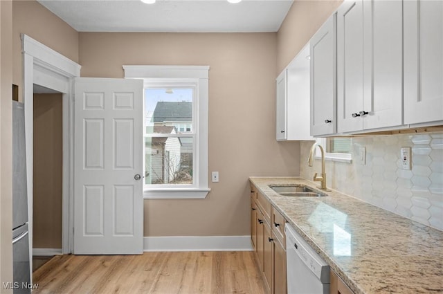 kitchen featuring a sink, light stone countertops, backsplash, and dishwasher