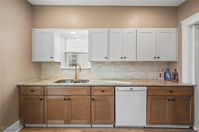 kitchen featuring a sink, light stone countertops, tasteful backsplash, and dishwasher