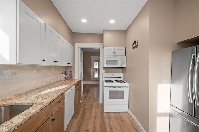 kitchen with white appliances, baseboards, light wood finished floors, white cabinetry, and tasteful backsplash