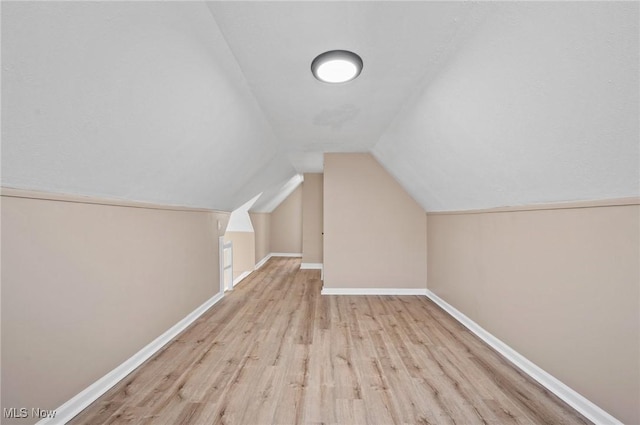 additional living space featuring wood finished floors, baseboards, and vaulted ceiling