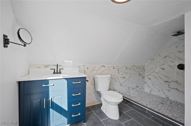 full bath featuring toilet, a marble finish shower, tile walls, lofted ceiling, and vanity