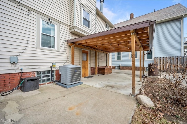 view of patio / terrace featuring central AC unit, concrete driveway, and fence