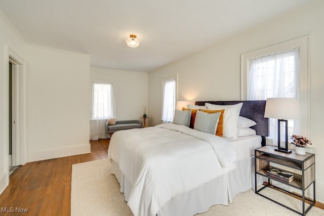 bedroom featuring crown molding, baseboards, and hardwood / wood-style floors