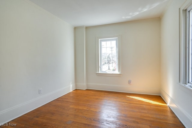 spare room with ornamental molding, baseboards, and hardwood / wood-style floors