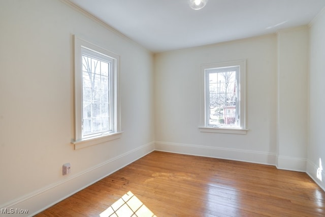 unfurnished room with plenty of natural light, baseboards, light wood-style floors, and ornamental molding