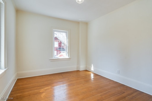 spare room featuring baseboards, crown molding, and light wood-style floors