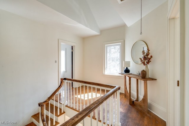 corridor featuring baseboards, an upstairs landing, dark wood-type flooring, and vaulted ceiling