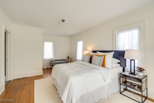 bedroom with hardwood / wood-style floors, crown molding, and baseboards