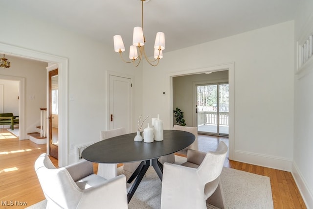 dining space with light wood finished floors, a notable chandelier, baseboards, and visible vents