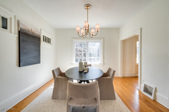 dining room featuring visible vents, baseboards, light wood-style flooring, and a chandelier