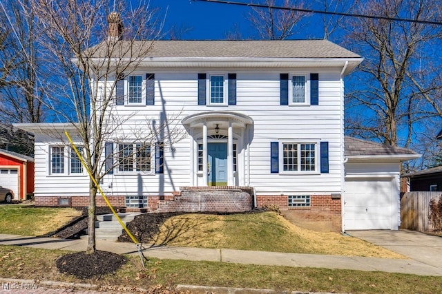 colonial home with a front lawn, concrete driveway, an attached garage, and a shingled roof