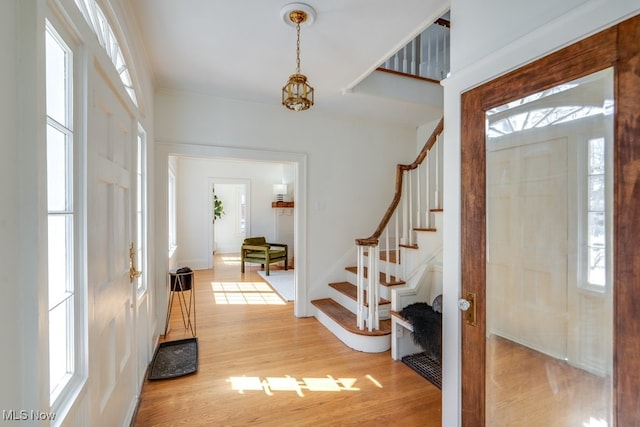 entrance foyer with light wood finished floors, stairs, and baseboards