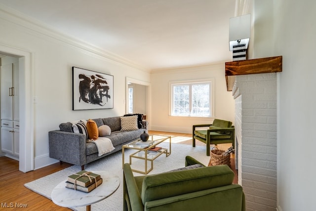 living room featuring baseboards, a brick fireplace, wood finished floors, and crown molding