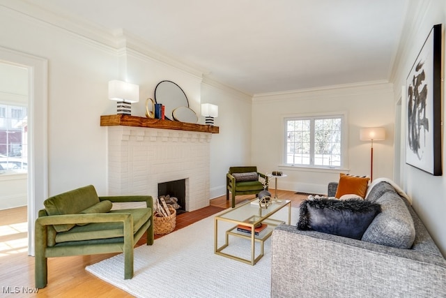 living area featuring ornamental molding, a brick fireplace, baseboards, and wood finished floors