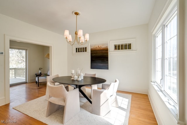 dining room featuring baseboards, light wood-style floors, and an inviting chandelier