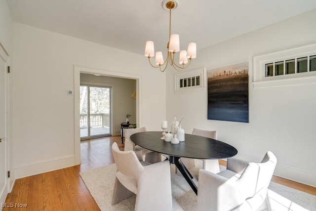 dining area featuring light wood-style floors, baseboards, and a notable chandelier