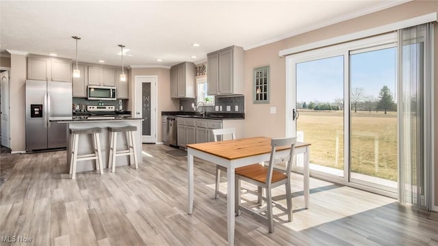 kitchen featuring ornamental molding, gray cabinets, dark countertops, appliances with stainless steel finishes, and decorative backsplash