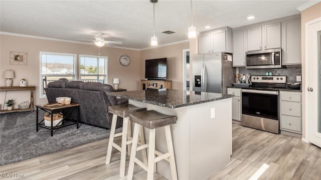 kitchen featuring decorative backsplash, crown molding, appliances with stainless steel finishes, and a center island