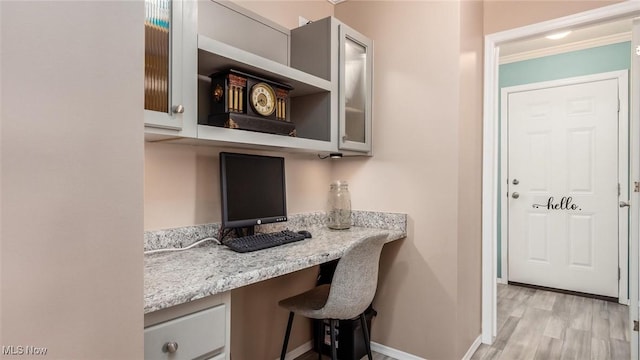 office space featuring built in study area, light wood-type flooring, and baseboards