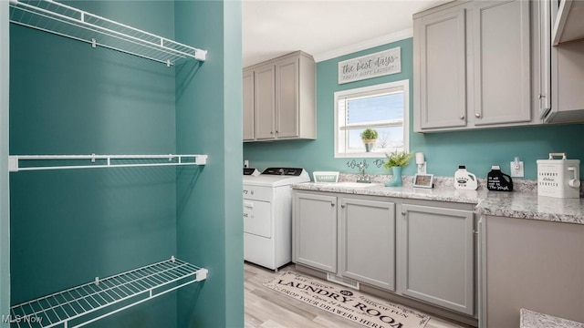 laundry room featuring a sink, cabinet space, light wood finished floors, and washer and clothes dryer