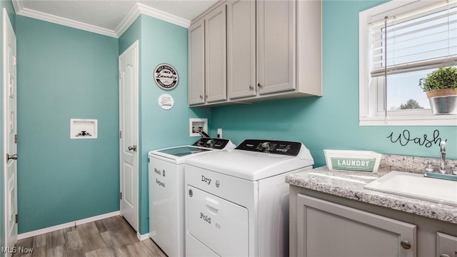 washroom featuring light wood-style flooring, cabinet space, a sink, crown molding, and washer and clothes dryer