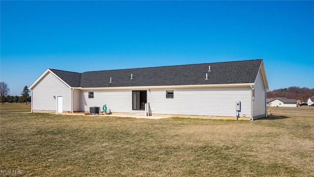 back of property with central air condition unit and a yard