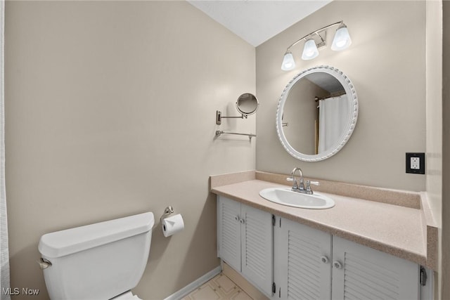 bathroom featuring baseboards, toilet, and vanity