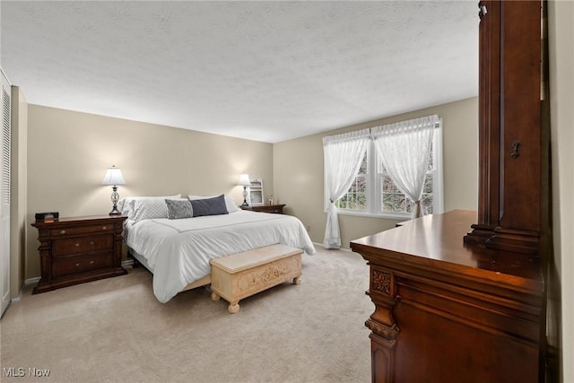 bedroom featuring light colored carpet, baseboards, and a textured ceiling