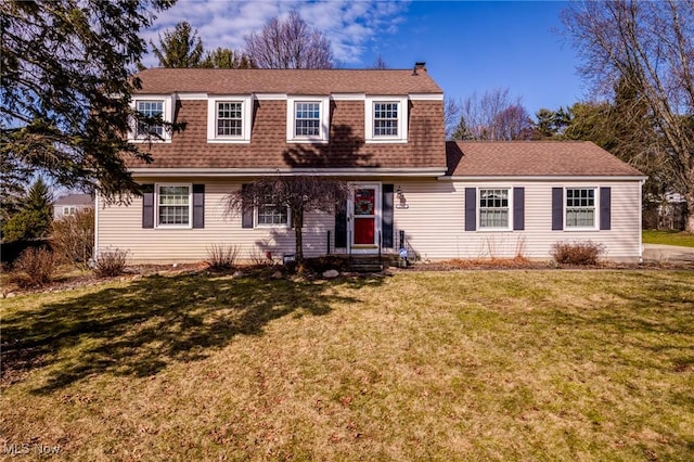 colonial inspired home with entry steps, a front yard, and a shingled roof