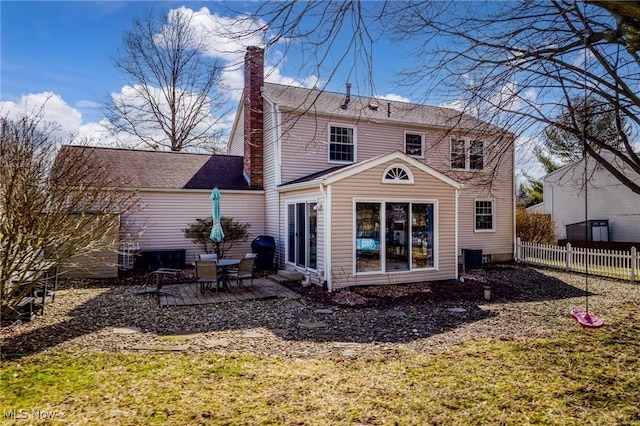 back of house featuring a chimney and fence