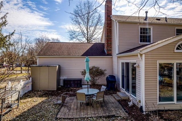 exterior space featuring a chimney, roof with shingles, a patio, and fence