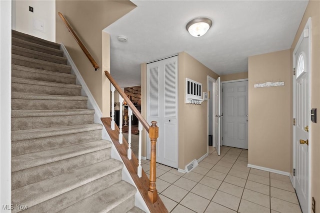 foyer with light tile patterned floors, stairs, and baseboards