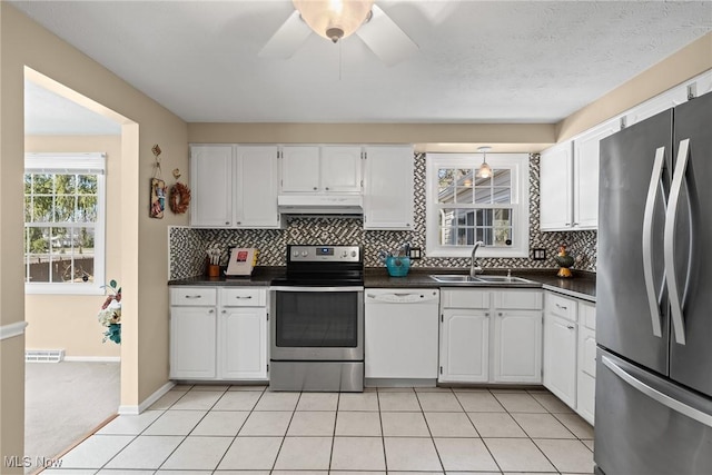 kitchen with dark countertops, visible vents, under cabinet range hood, stainless steel appliances, and a sink