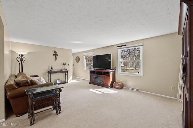 living area with light colored carpet, visible vents, and a textured ceiling