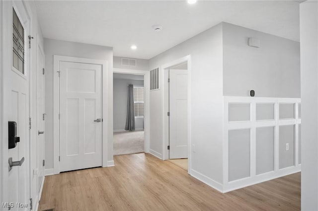 hallway featuring baseboards, visible vents, and light wood finished floors