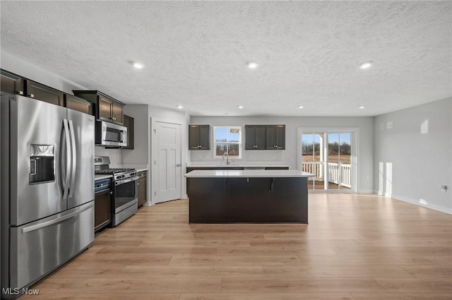 kitchen with a center island, light wood-type flooring, light countertops, recessed lighting, and stainless steel appliances