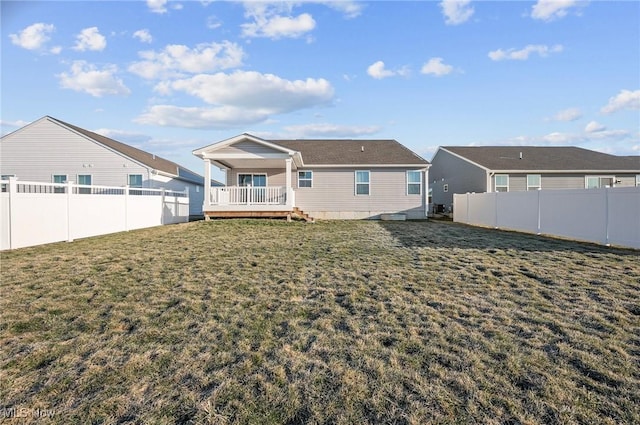 rear view of property featuring a lawn, a fenced backyard, and a wooden deck