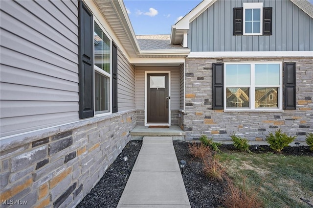 property entrance with board and batten siding and stone siding