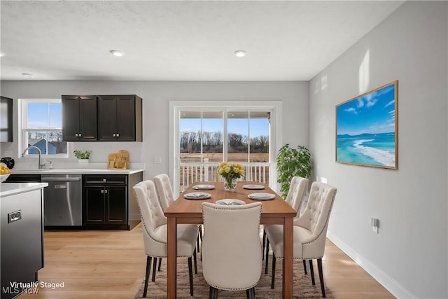 dining area with baseboards, a healthy amount of sunlight, and light wood-style flooring