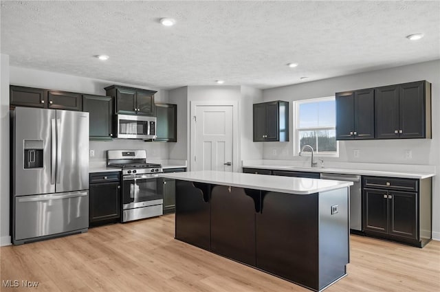 kitchen featuring a sink, a kitchen island, appliances with stainless steel finishes, a breakfast bar area, and light wood finished floors