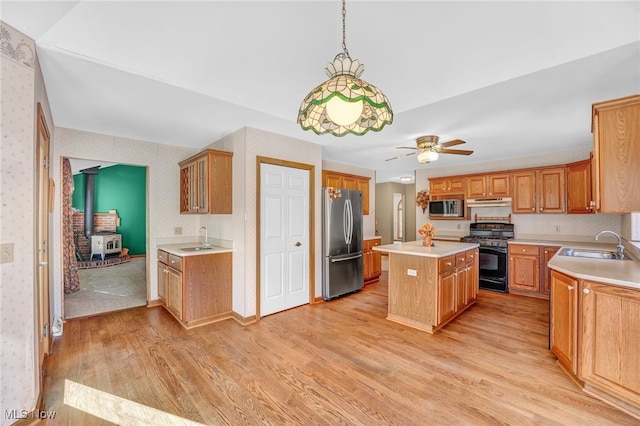 kitchen with a sink, appliances with stainless steel finishes, light countertops, and wallpapered walls