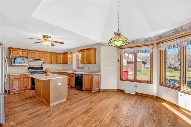 kitchen with black appliances, light wood-style flooring, under cabinet range hood, wallpapered walls, and light countertops