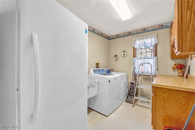 laundry area featuring cabinet space, a textured ceiling, and separate washer and dryer