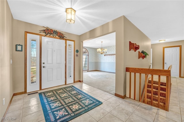 foyer featuring light tile patterned flooring, baseboards, wallpapered walls, and an inviting chandelier